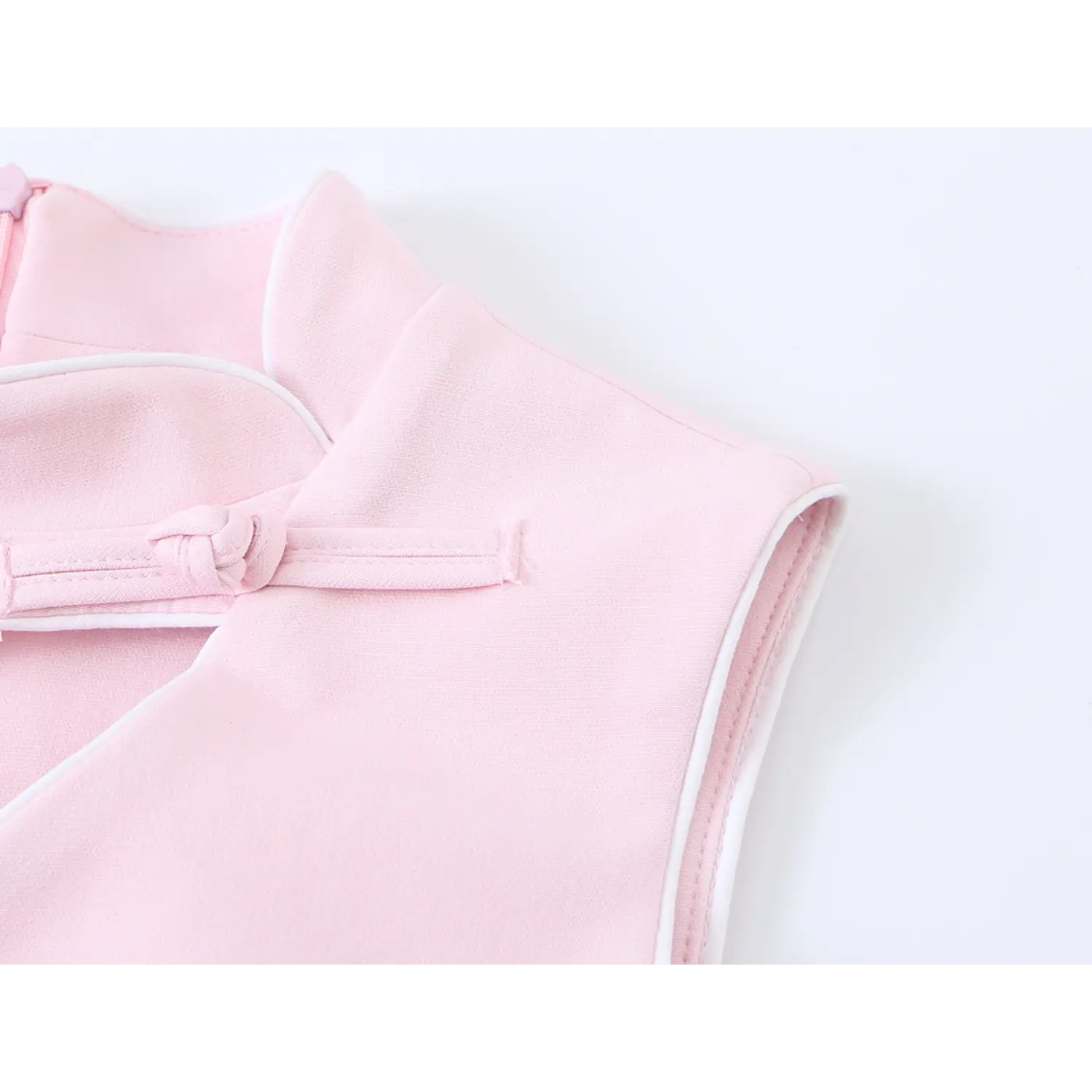 Partial closeup of stand collar, armhole white piping and top frog button on light pink cheongsam mini dress
