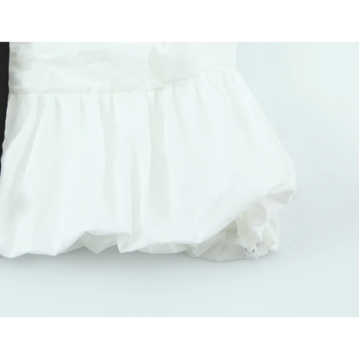 Close-up of the hem on the white ruffle top, showing the puffy bubble hem, gathered fabric, and clean seam