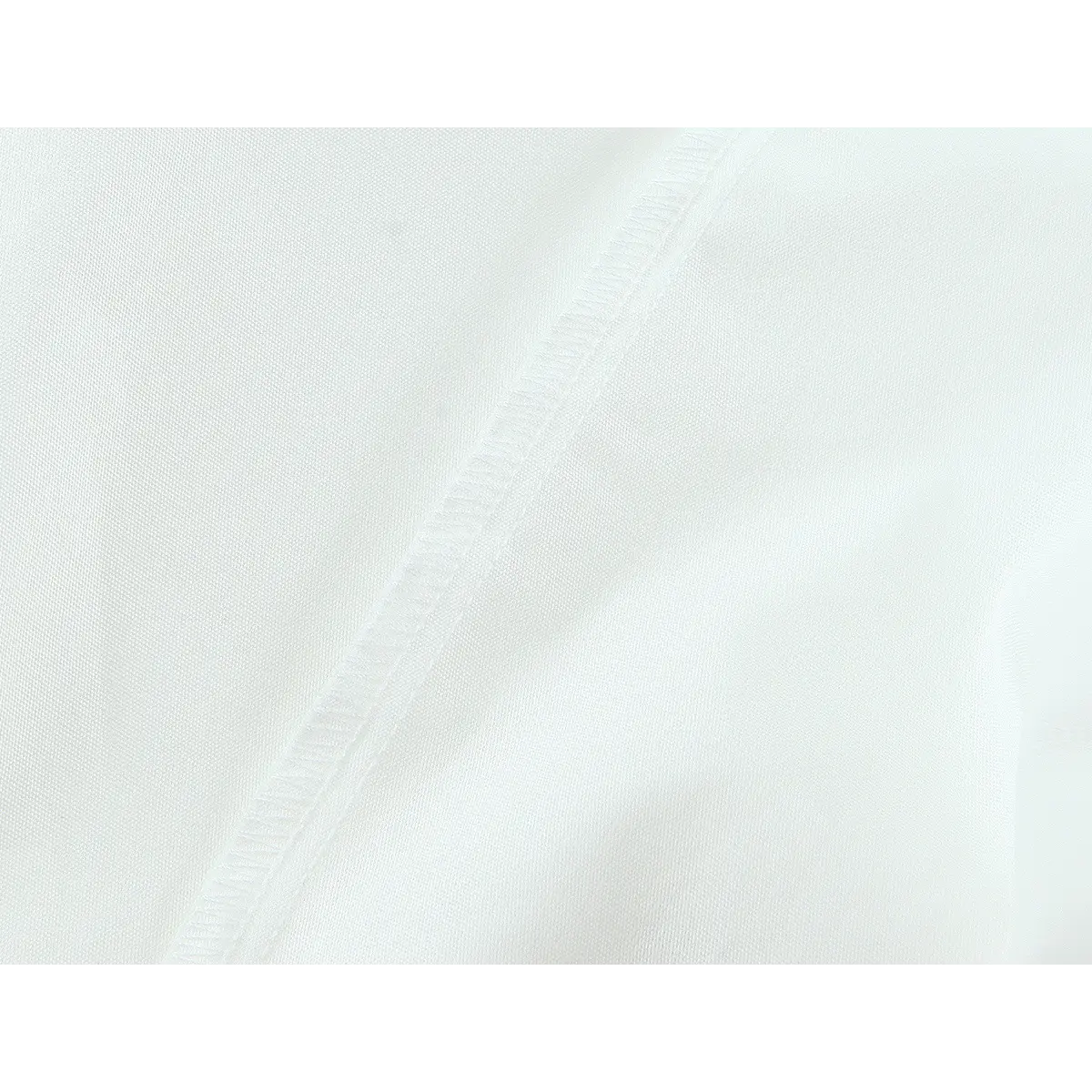 Close-up of the side seam on the white top, showing the smooth fabric and precise stitching