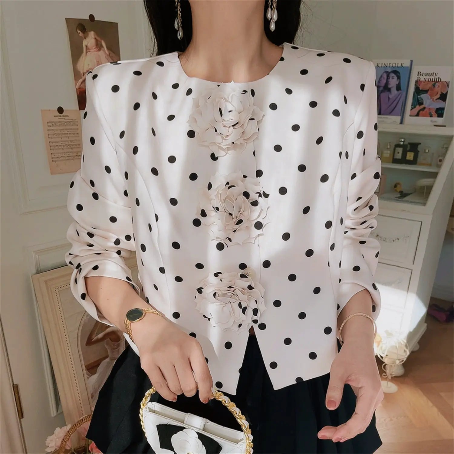 Close-up model shot of white black polka dot cropped jacket with three 3D fabric rose flowers, round neck long sleeve outerwear
