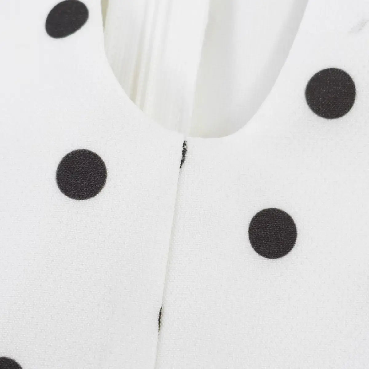 Close-up of the V-neck placket, showing the stitching and polka dot print alignment.