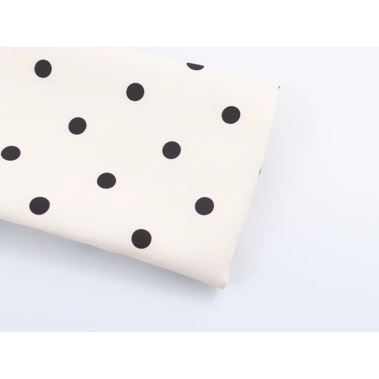 Fabric texture close-up, white base with evenly printed black polka dots