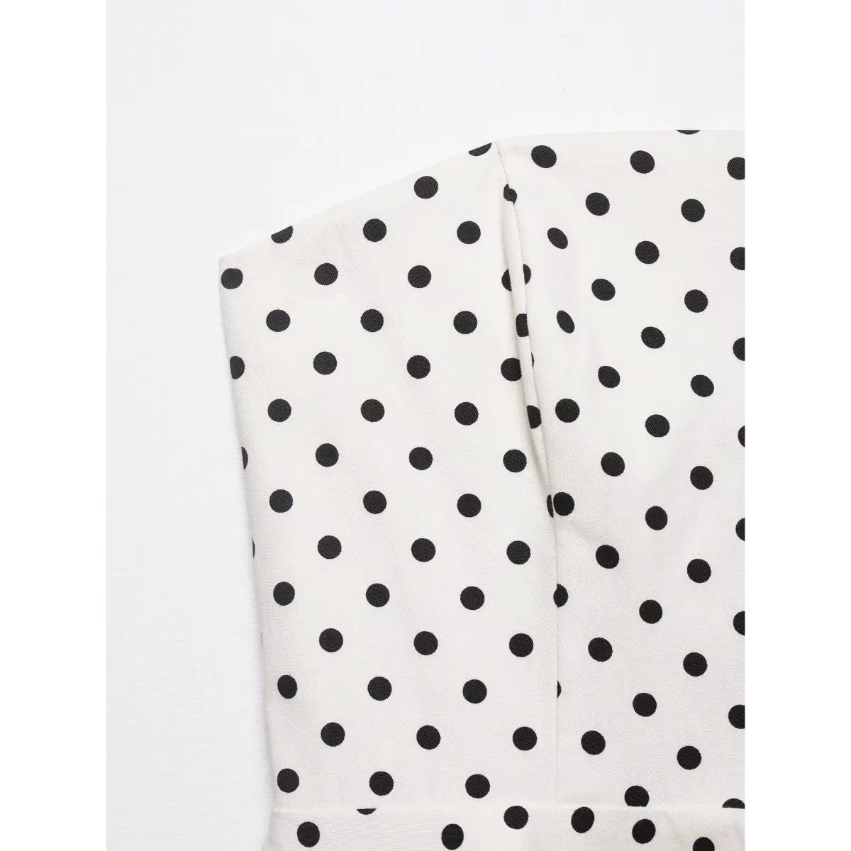 Close-up of the black polka dot pattern and fabric texture on the white strapless top