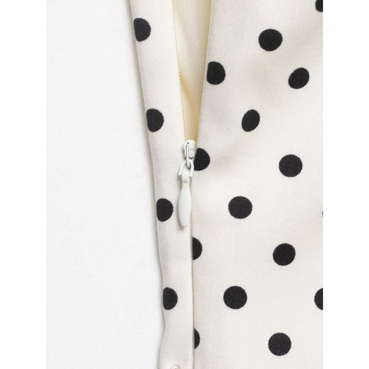 Close-up of the invisible side zipper on the white polka dot strapless top