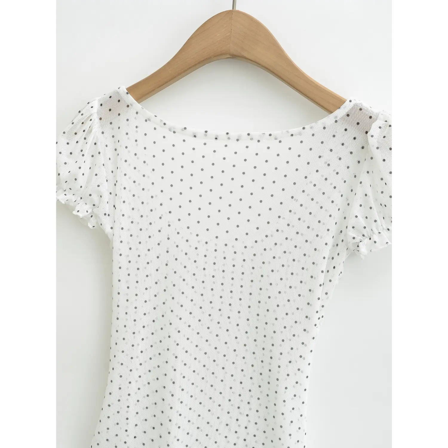 Full front hanging view on wood hanger, white mesh polka dot top with square neck, bubble sleeves and ruched waist hem