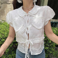 Slight angle view of the white embroidered puff-sleeve blouse, showing the silhouette and eyelet details.
