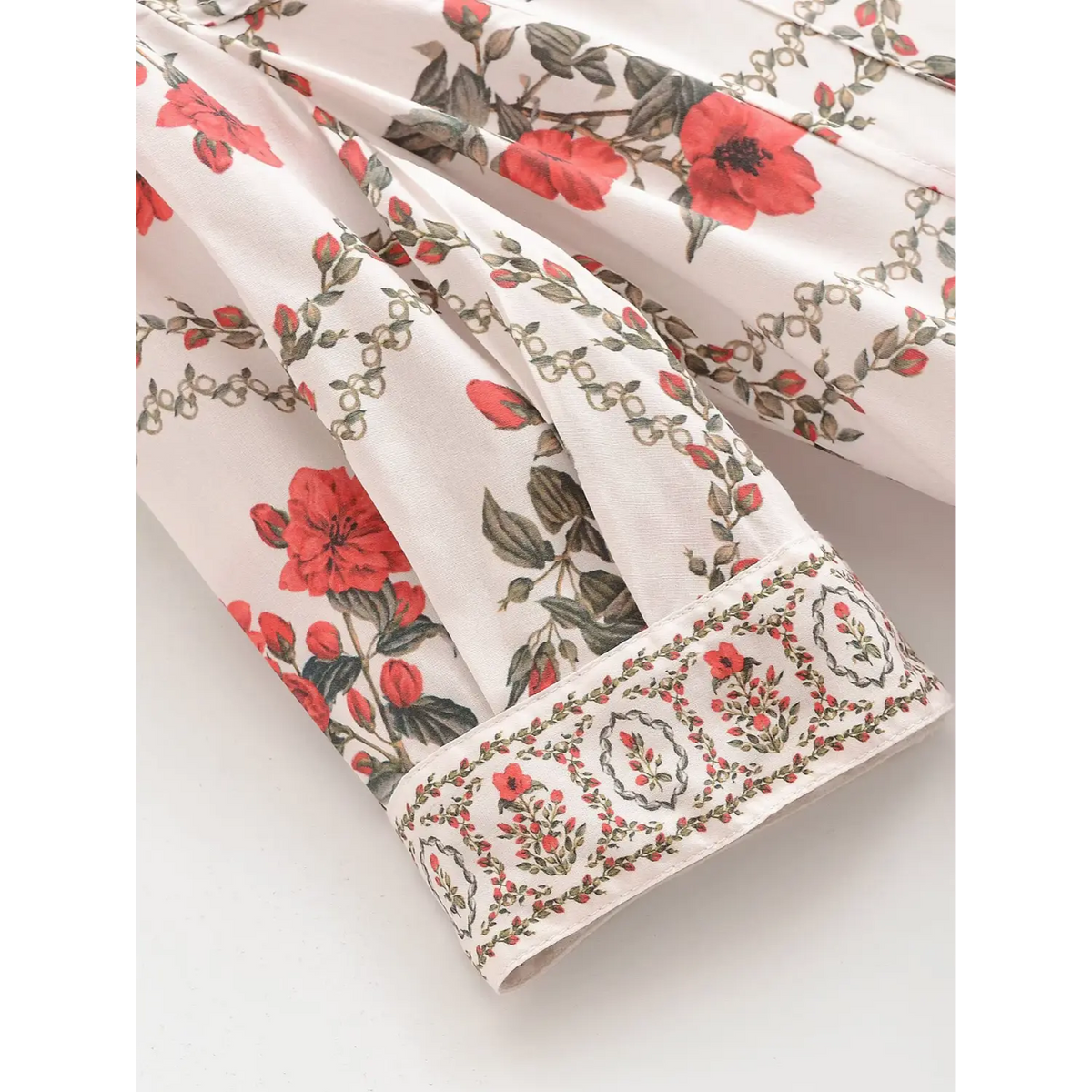 Sleeve cuff detail of white maxi dress with ornate red floral border print and finished edge