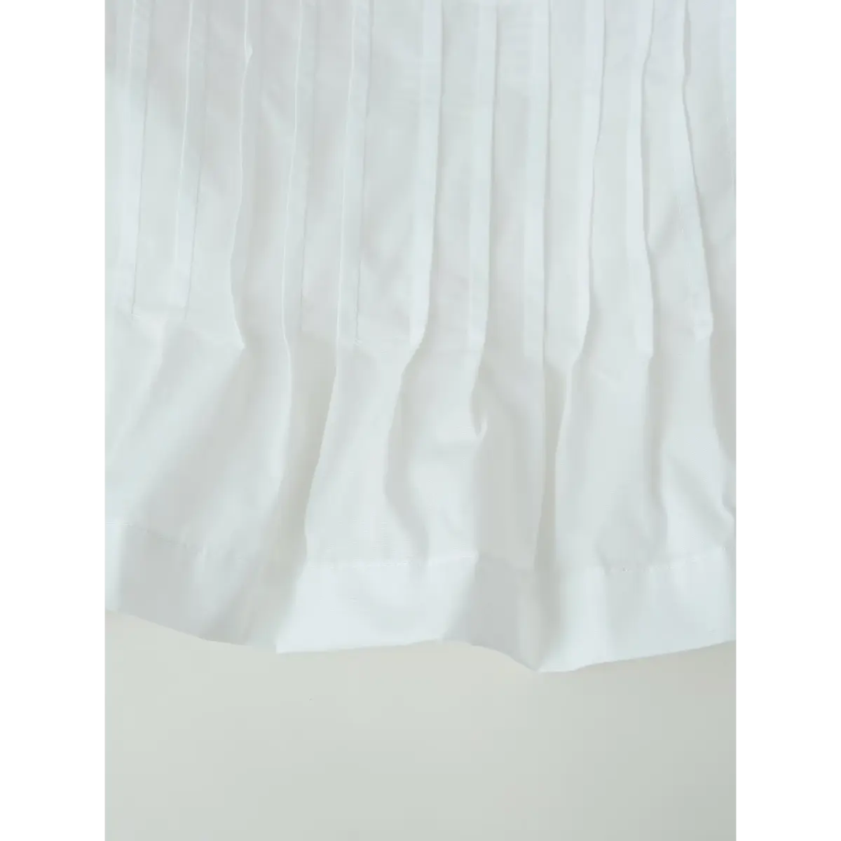 Close-up of the blouse's hem, showing the vertical pleats and clean finishing stitches.