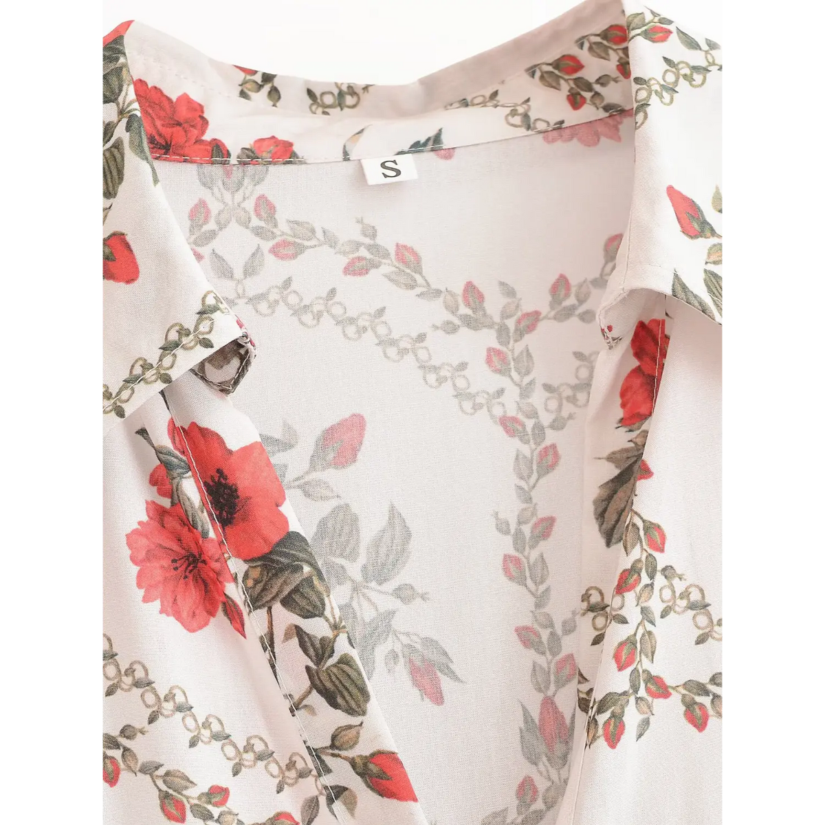 Macro closeup of shirt collar on white maxi dress, highlighting red floral print and decorative border pattern