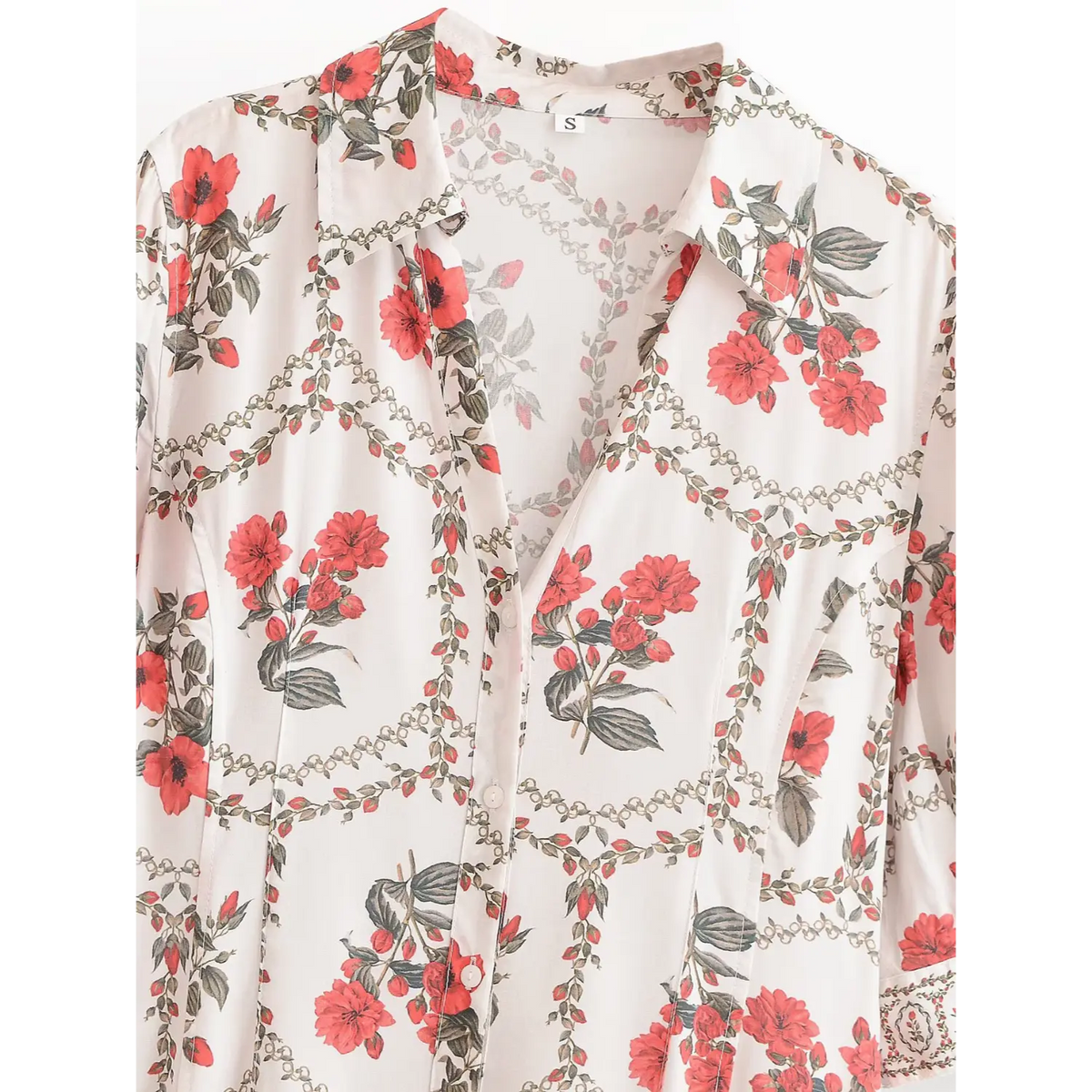 Close-up of collar and V-neck area on white maxi dress, featuring red flowers, green leaves and chain-link border print