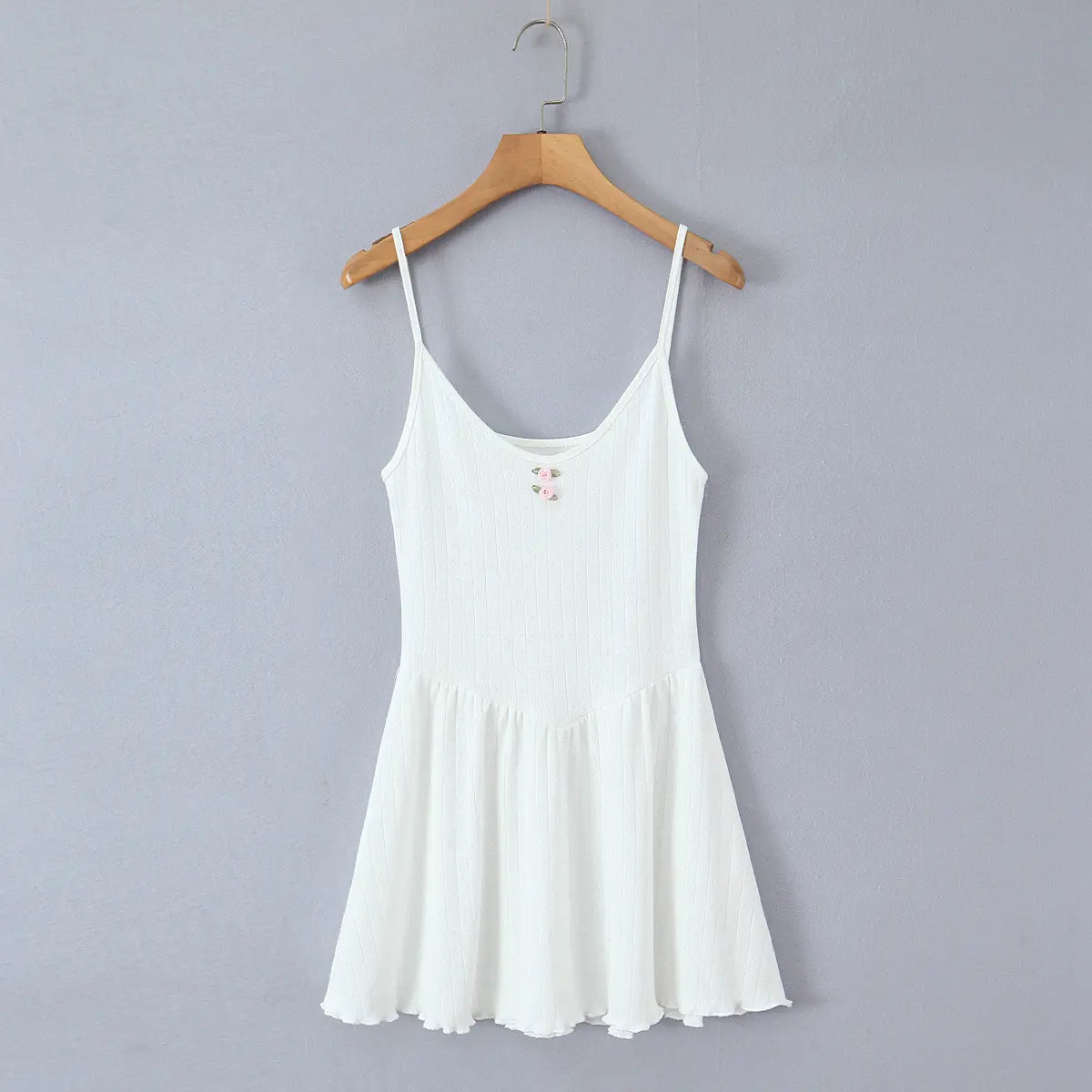  Full front view of the white ribbed cami dress, featuring a fitted bodice, flared skirt, and two small pink rose appliqués at the bust.