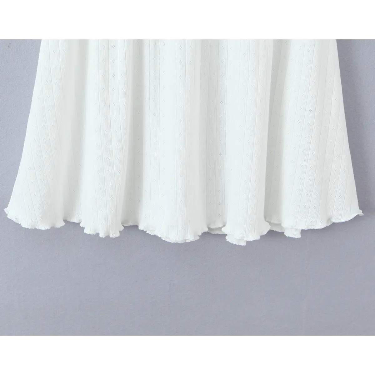 Close-up of the flared skirt hem, featuring the lettuce-edge finish and ribbed knit fabric.