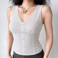 A woman wearing a white ribbed bustier tank top with V-neck lace trim, front buttons, and side lace panels, styled with a butterfly necklace and black bottoms.