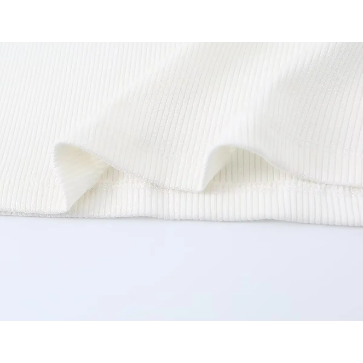 Close-up of the ribbed knit texture and stretch fabric on the white tank top