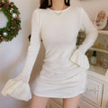 Side view of woman in cream fuzzy knit bodycon mini dress with big flared sleeve cuffs and waist gathering detail