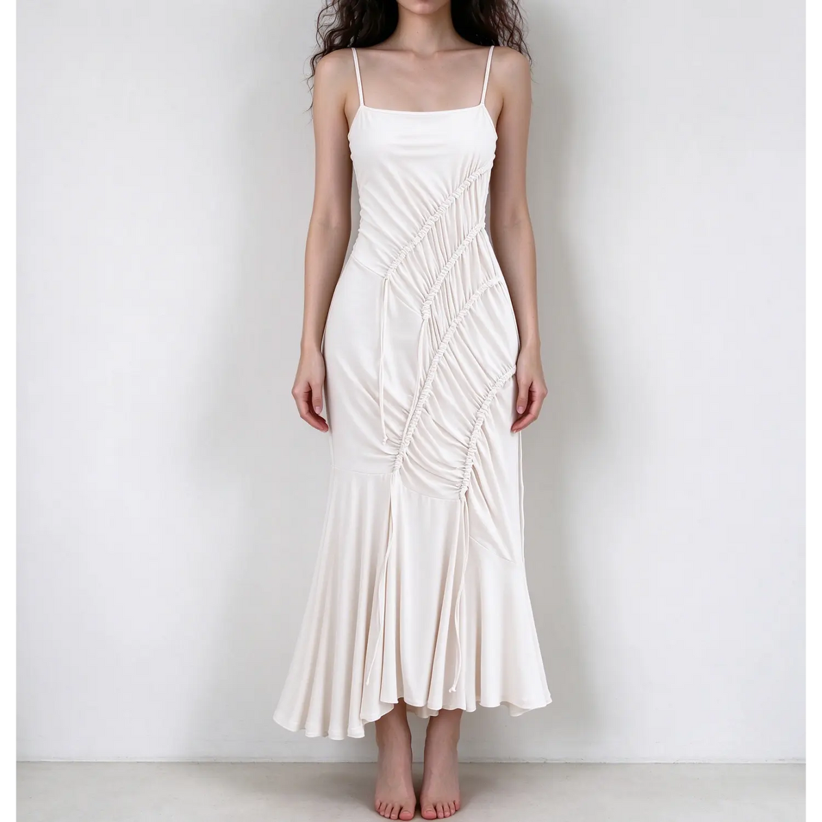 Model wearing white spaghetti strap maxi dress, diagonal drawstring ruched front, mermaid hem, stretch jersey fabric