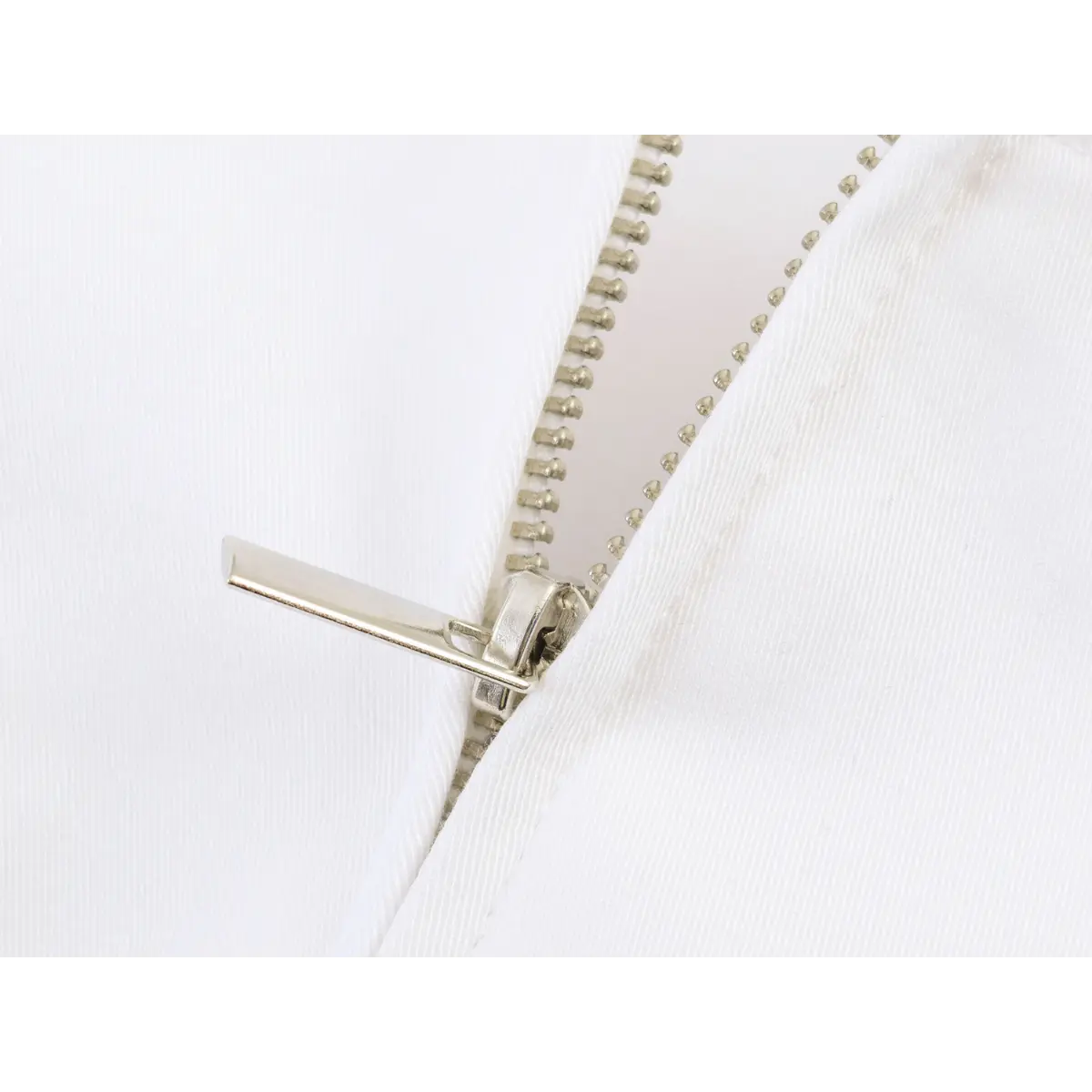 Close-up of the metal back zipper on the white ruffled cami top