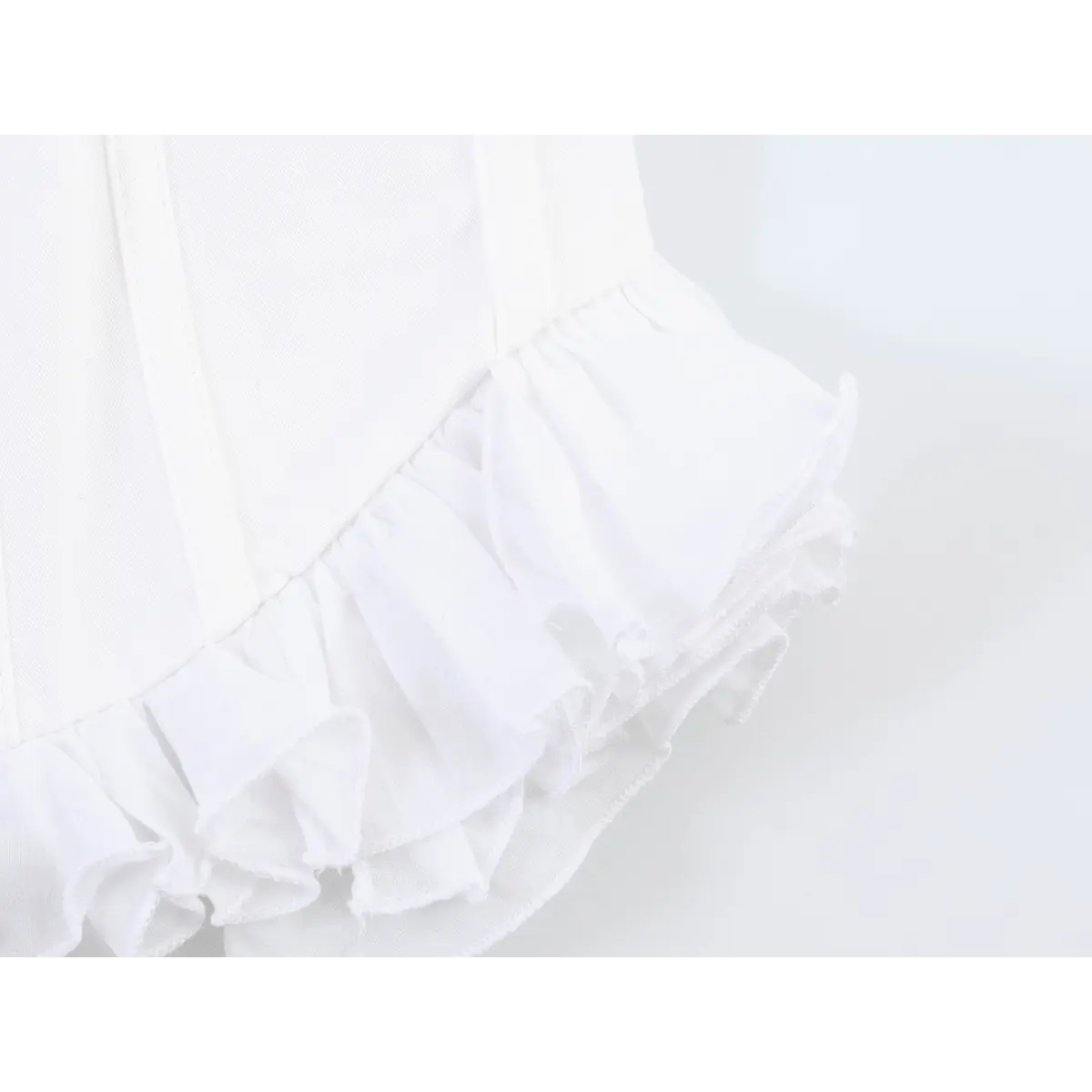 Close-up of the layered ruffled hem on the white corset-style cami top
