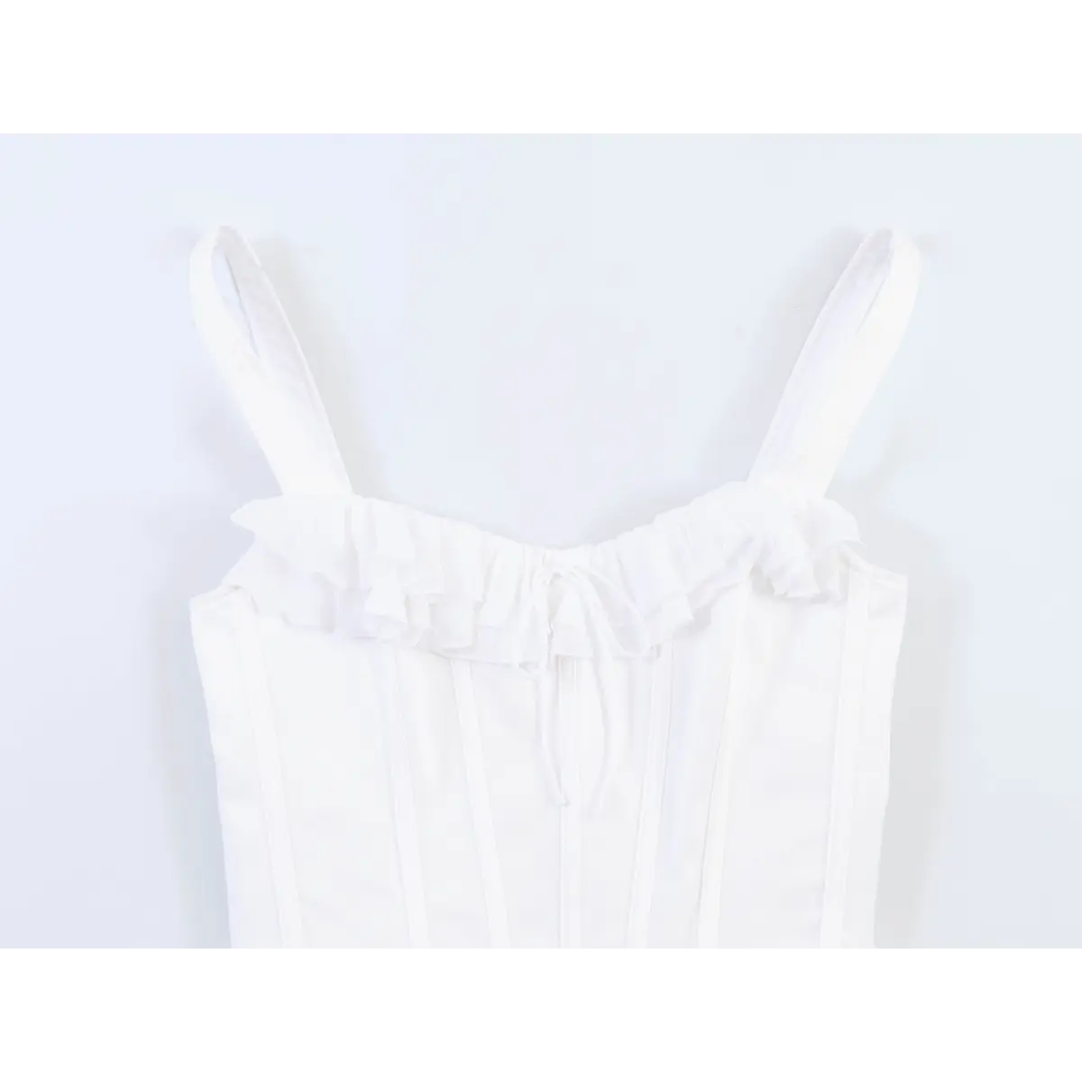 Close-up of the spaghetti straps and ruffled neckline on the white corset-style cami