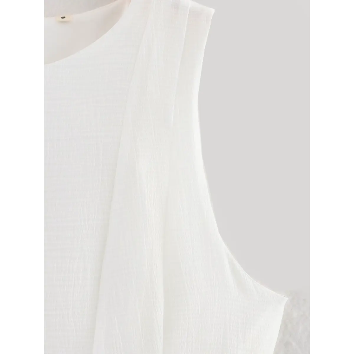 Top view of the dress's round neckline, sleeveless armholes, and front panel seams.