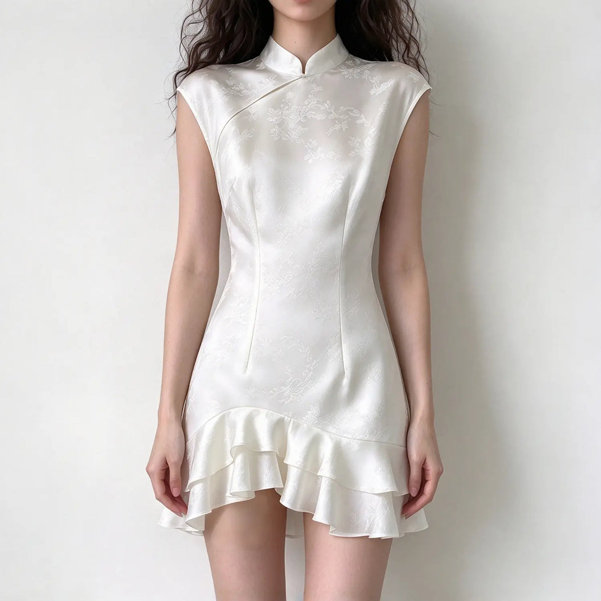 Model wearing white satin jacquard cheongsam style mini dress, mandarin collar, cap sleeve, ruffle asymmetrical hem, plain white background