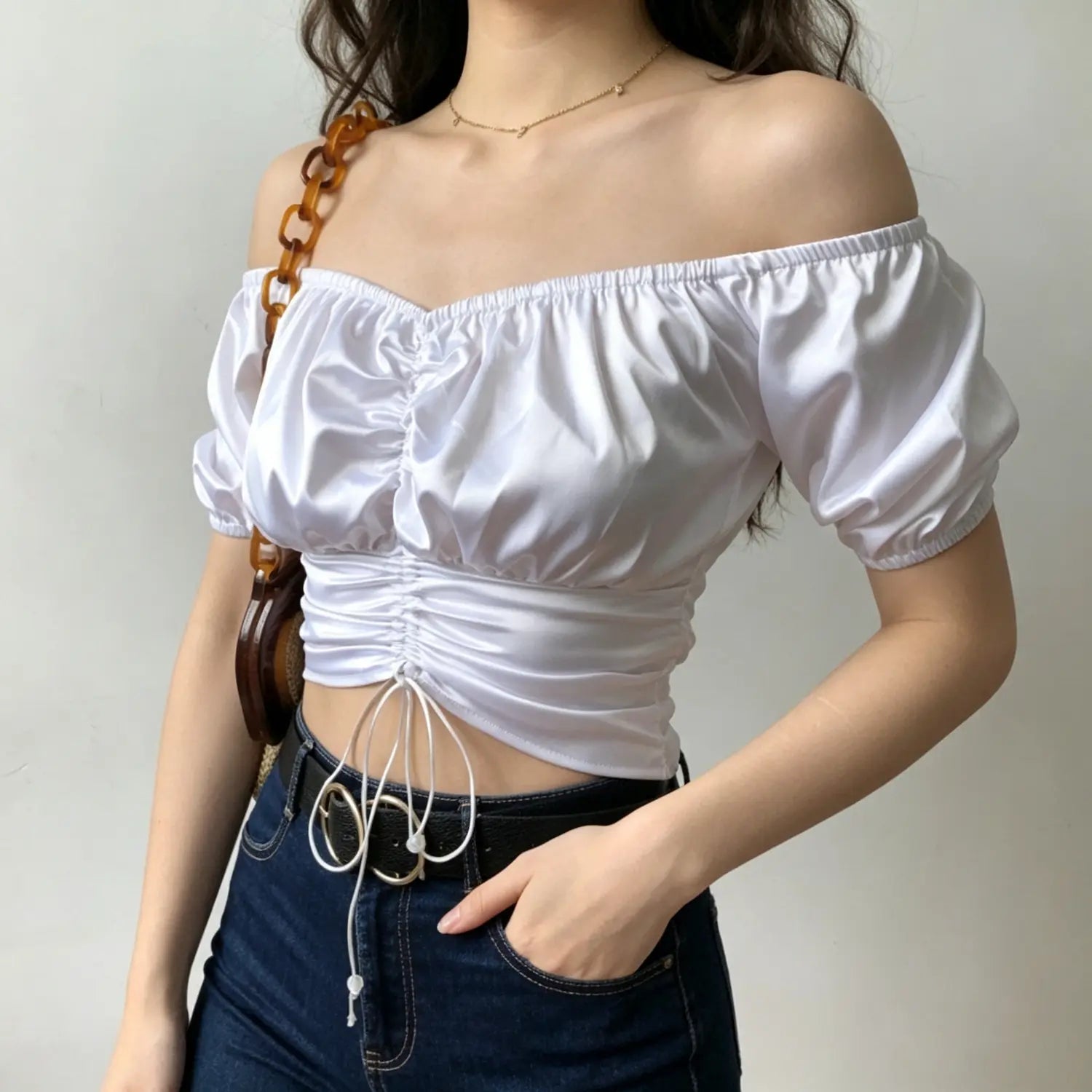 Model wearing white satin off shoulder puff short sleeve ruched front drawstring crop top