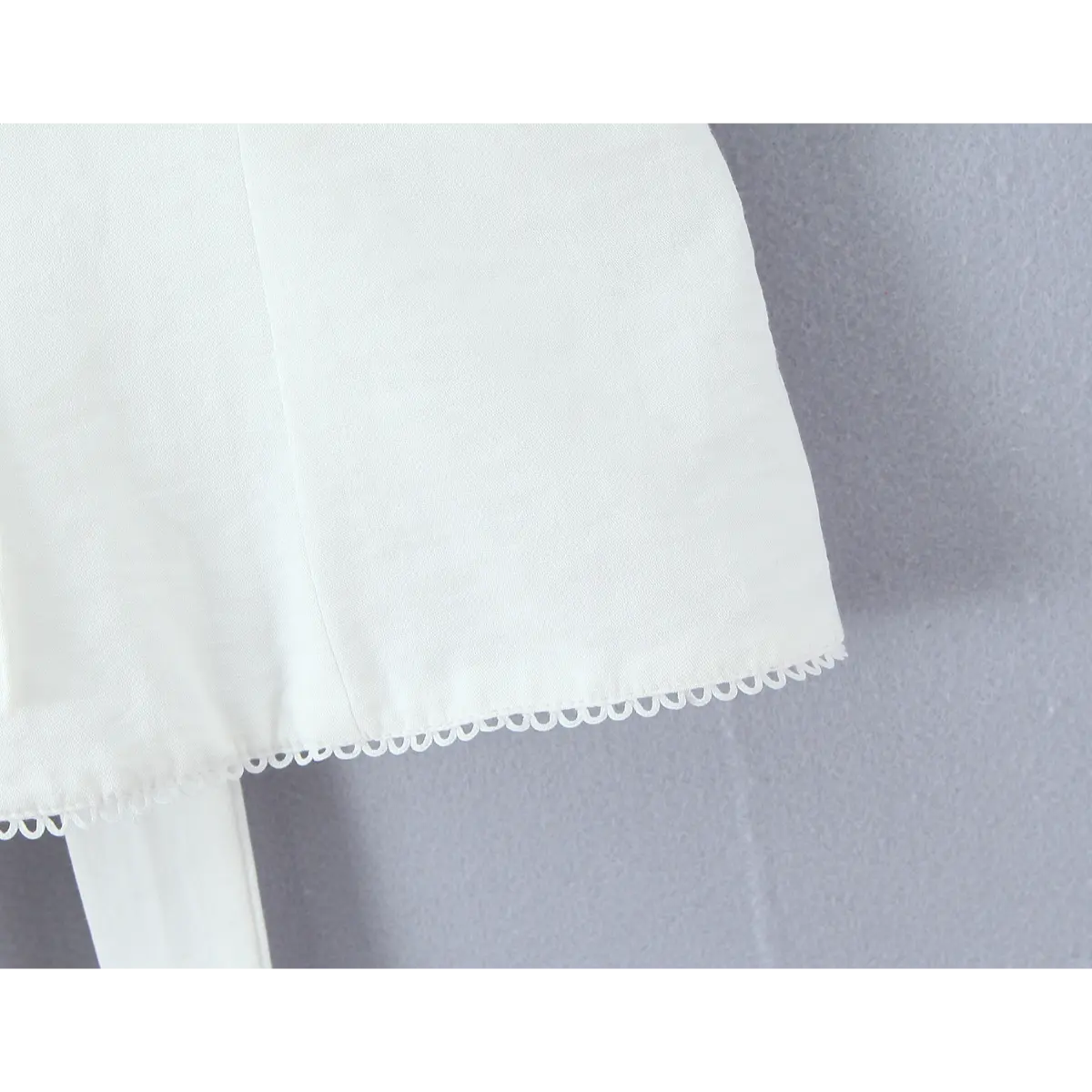 Close-up of the neatly finished scalloped lace hem on the white camisole.