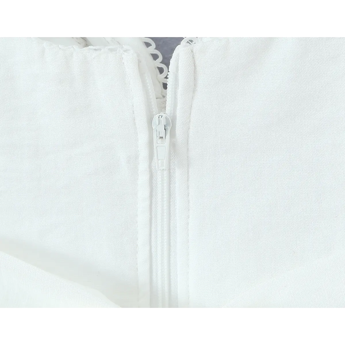 Close-up of the invisible center-back zipper on the white lace-trimmed camisole.