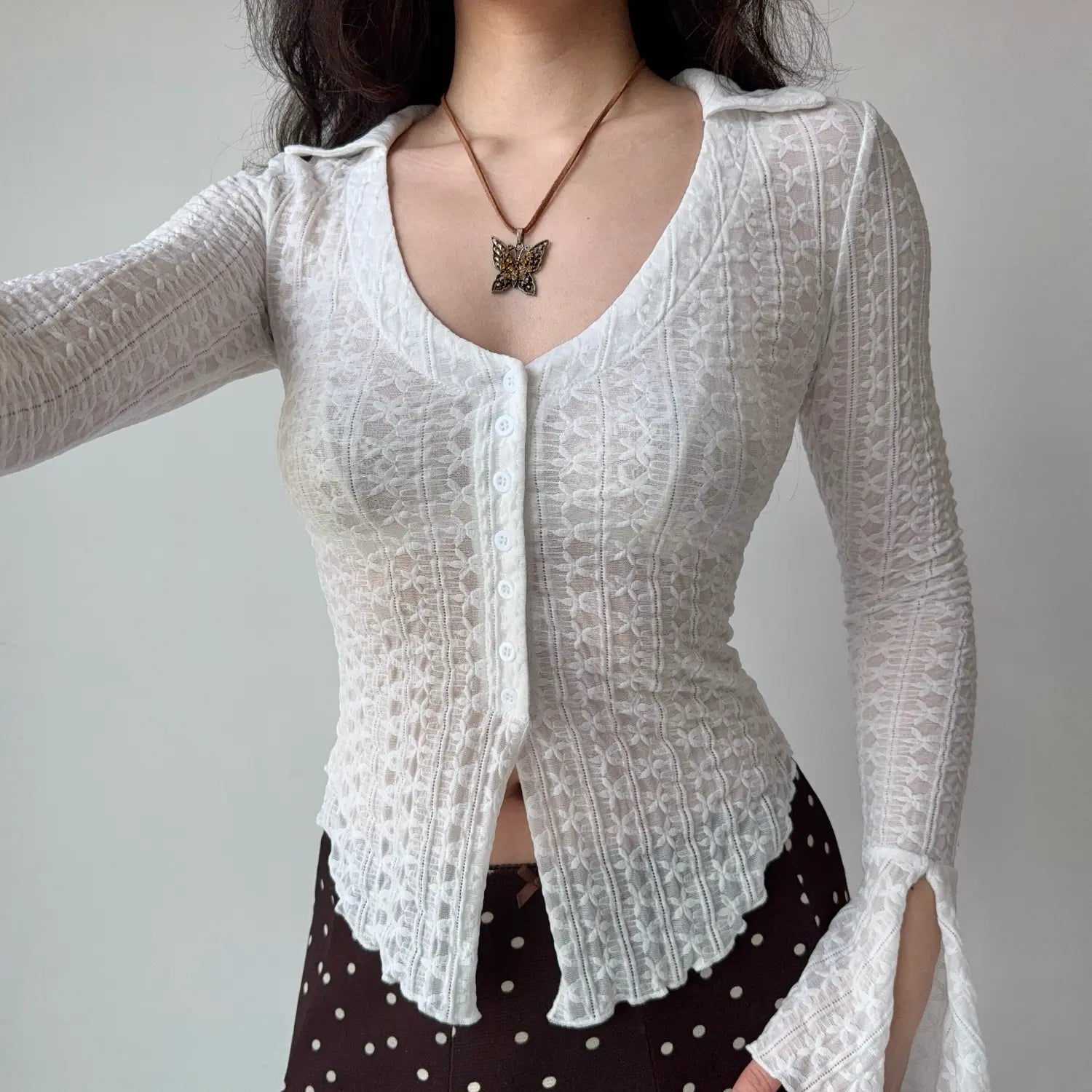 Model front pose arms out white sheer lace collared button‑front long sleeve top semi‑transparent floral lace fabric
