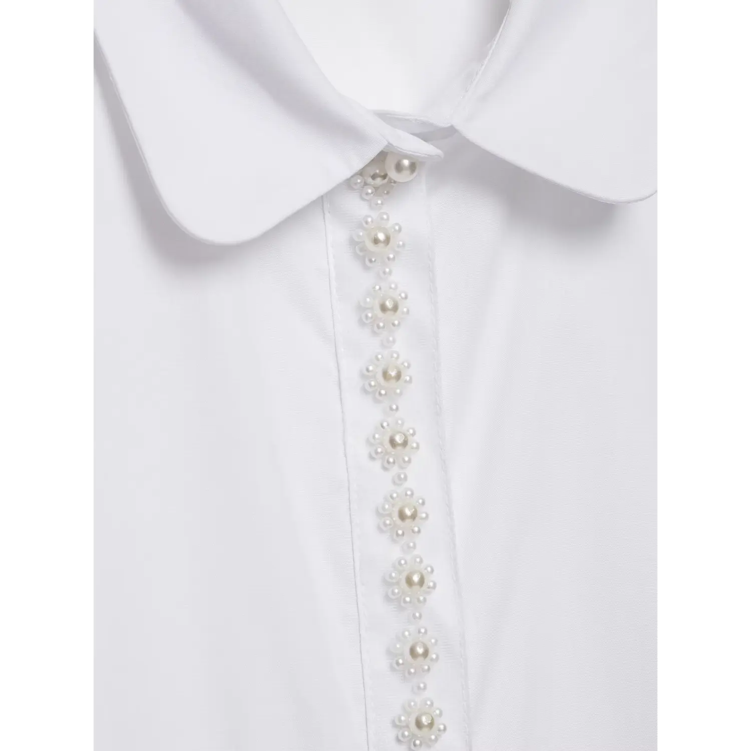 Close up floral pearl decoration on front placket of white collared blouse