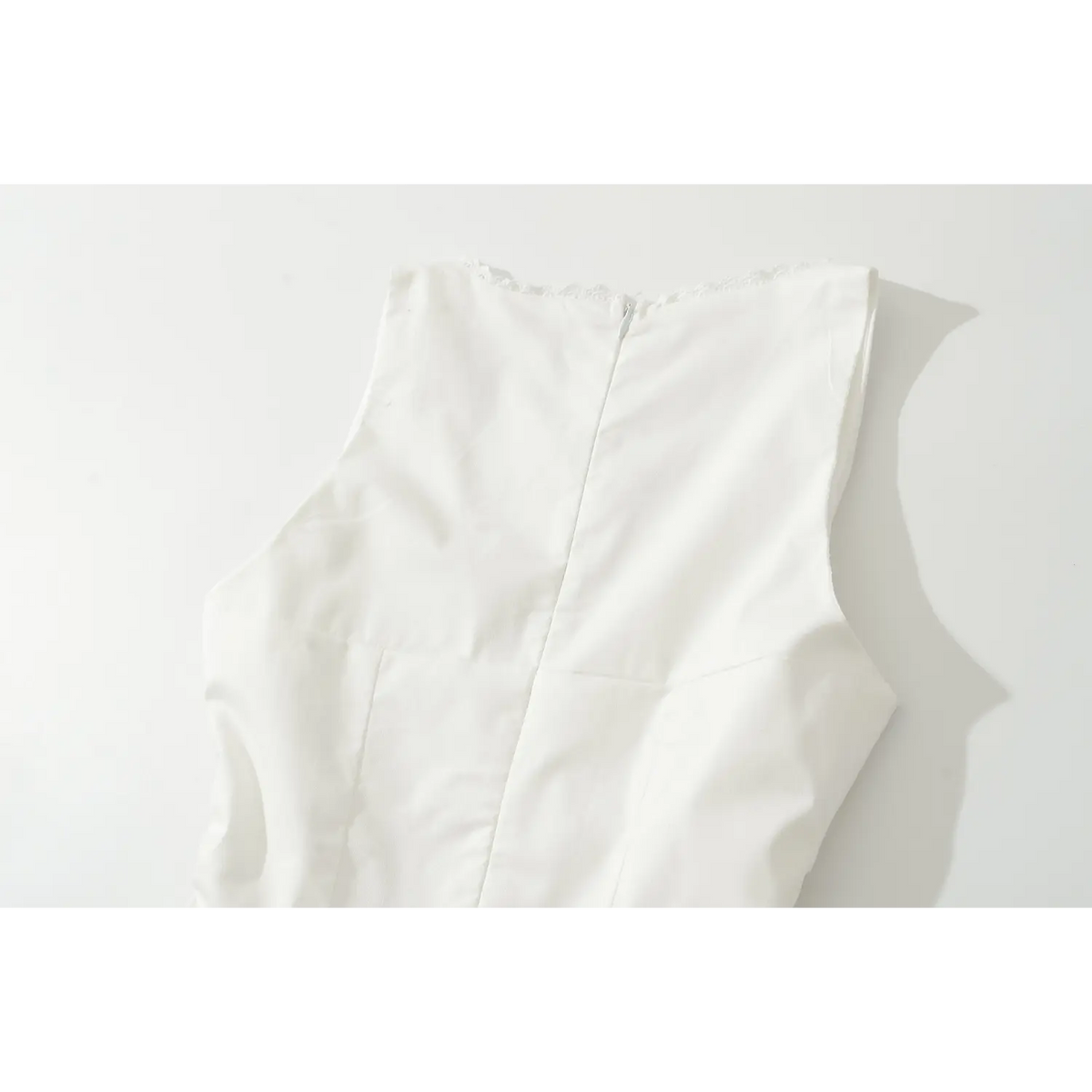 Back view of white sleeveless mini dress, hidden zipper, lace trim at neckline