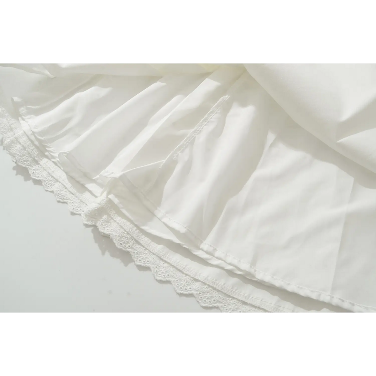 Close up view of white sleeveless mini dress, scalloped lace hem, soft fabric lining