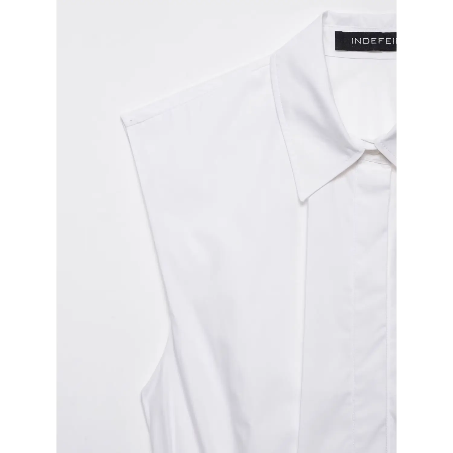 Collar and shoulder detail close-up of white sleeveless peplum shirt