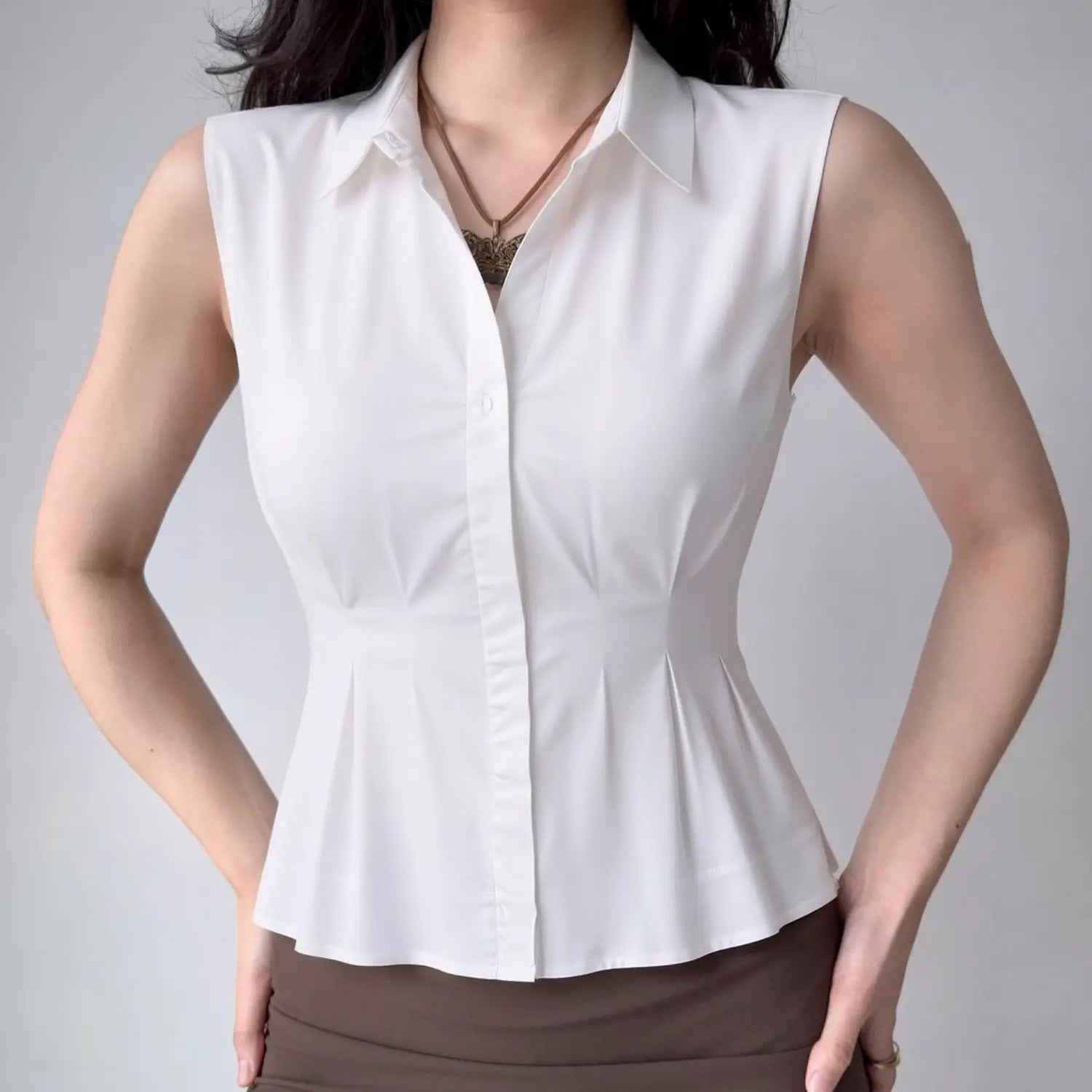 Model front view wearing white sleeveless collared peplum shirt, casual fitted outfit
