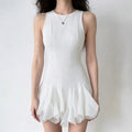 Model wearing a sleeveless white mini dress with a textured fabric, fitted bodice, and dramatic ruffled flounce hem.