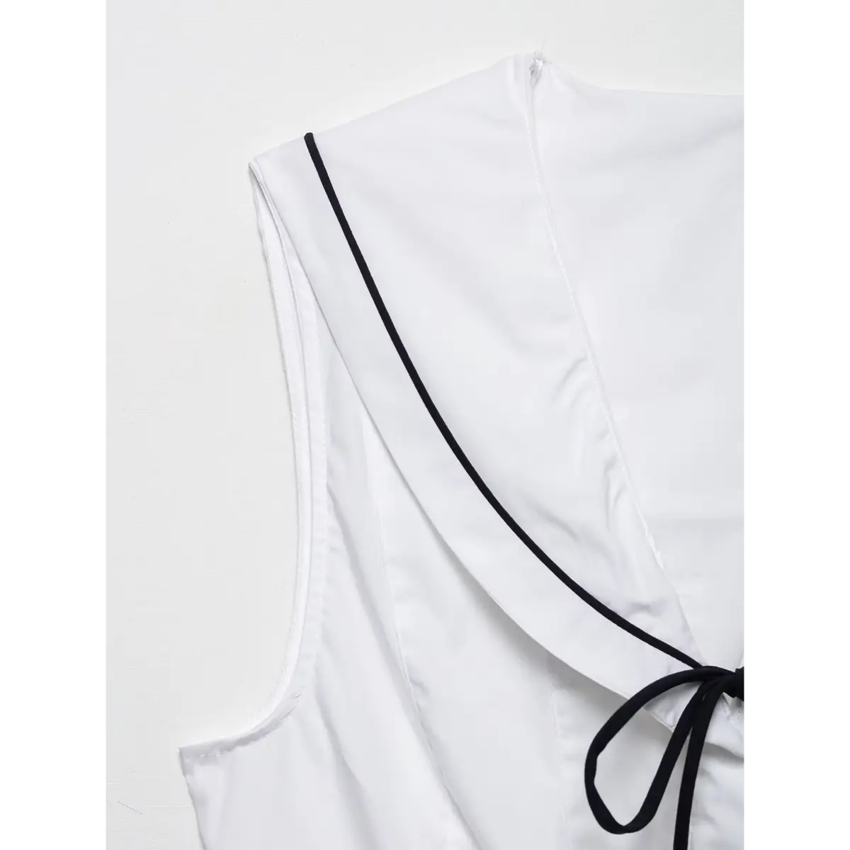Studio shot of the white sleeveless tie-front peplum top, front view.