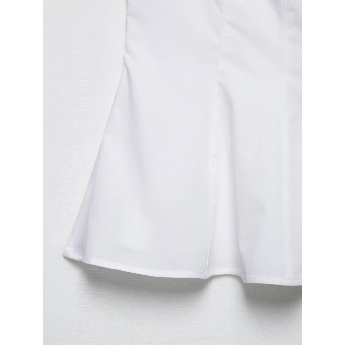 Close-up of the flared peplum hem on the white sleeveless top.