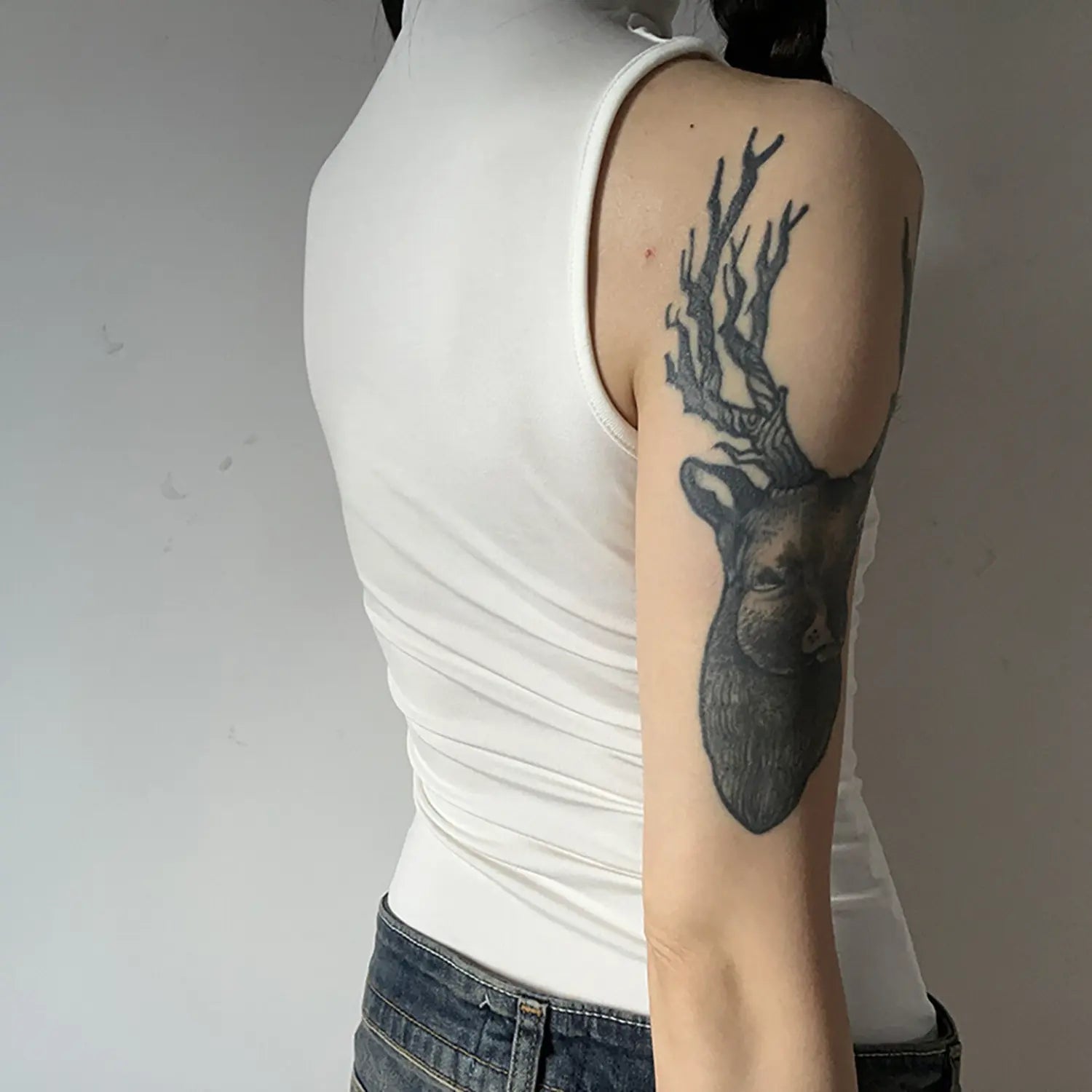 Back side torso view, model wearing white sleeveless turtleneck tank top, show back cut and armhole