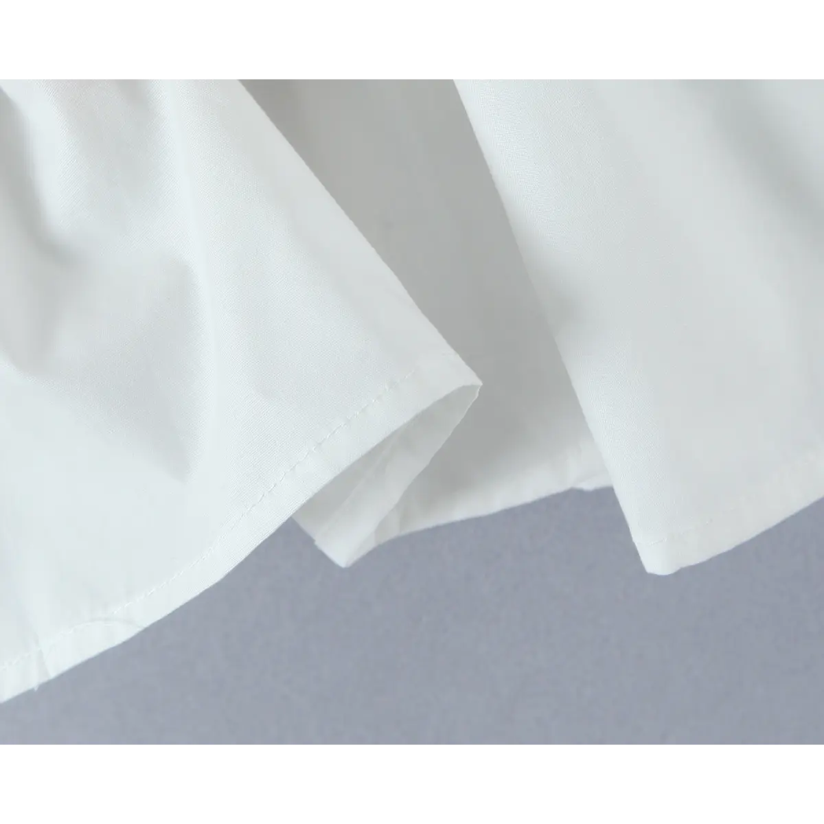 Close-up of flared peplum hem with lightweight smooth fabric and neat stitching.