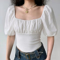 Front lifestyle shot on model of white square neck mixed fabric cropped top, gathered bust, balloon puff sleeves, slim curved shark hem, vintage casual outfit