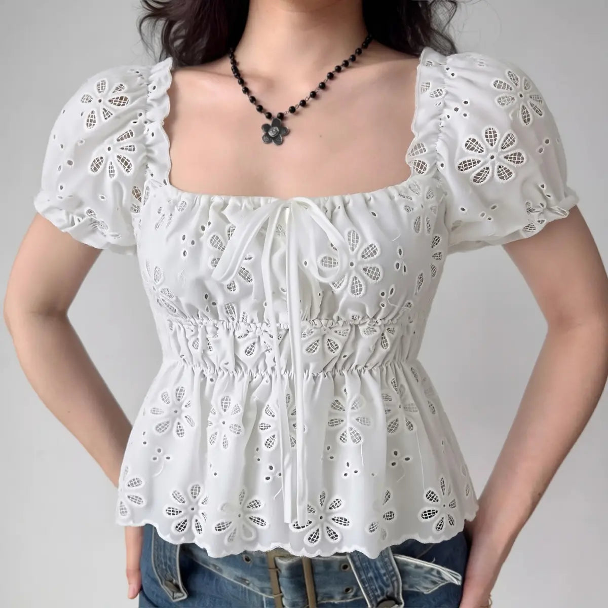 Woman wearing white square-neck eyelet embroidered top with puff sleeves, full front view