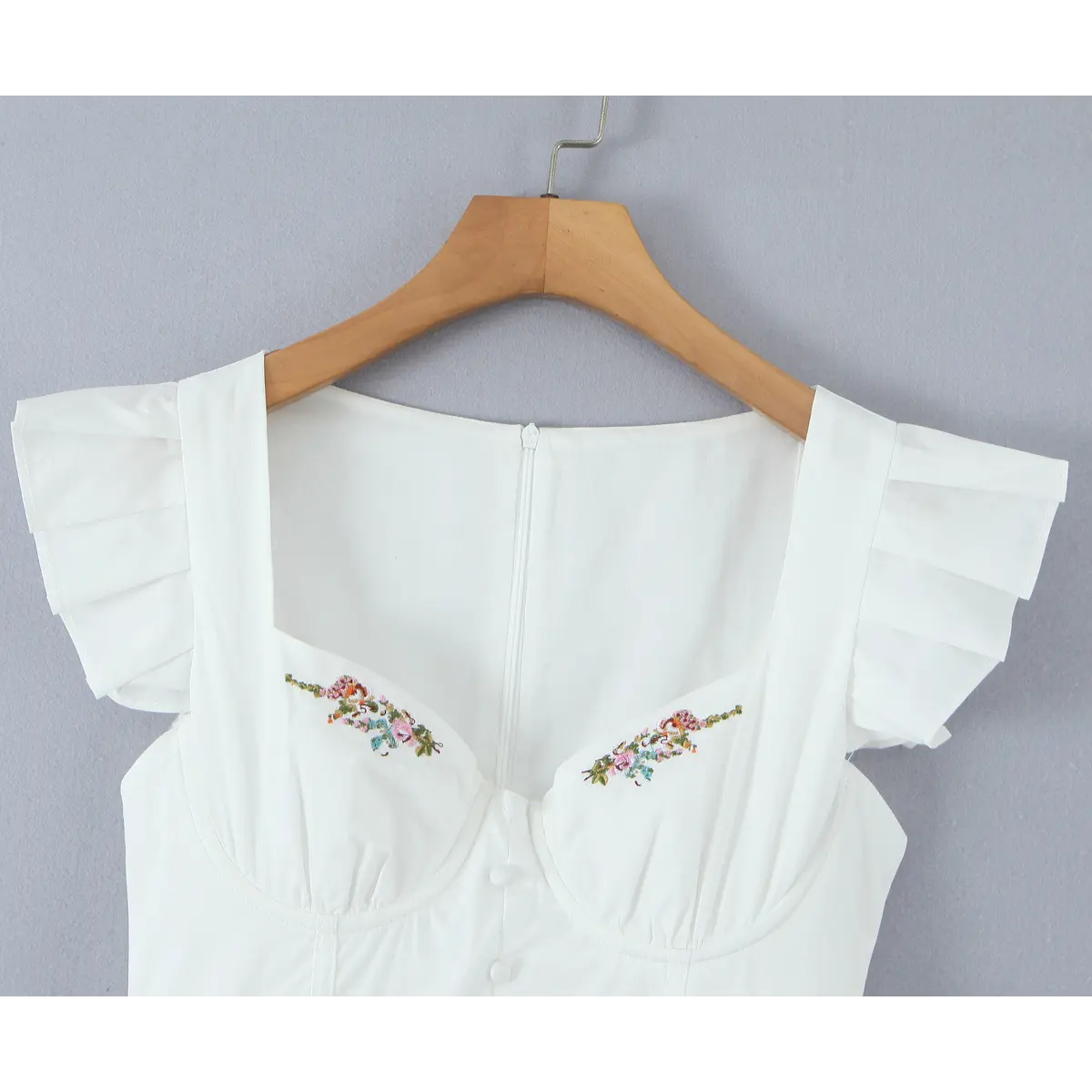 Front studio shot of the white dress, showing the square neckline, embroidery, and flutter sleeves.