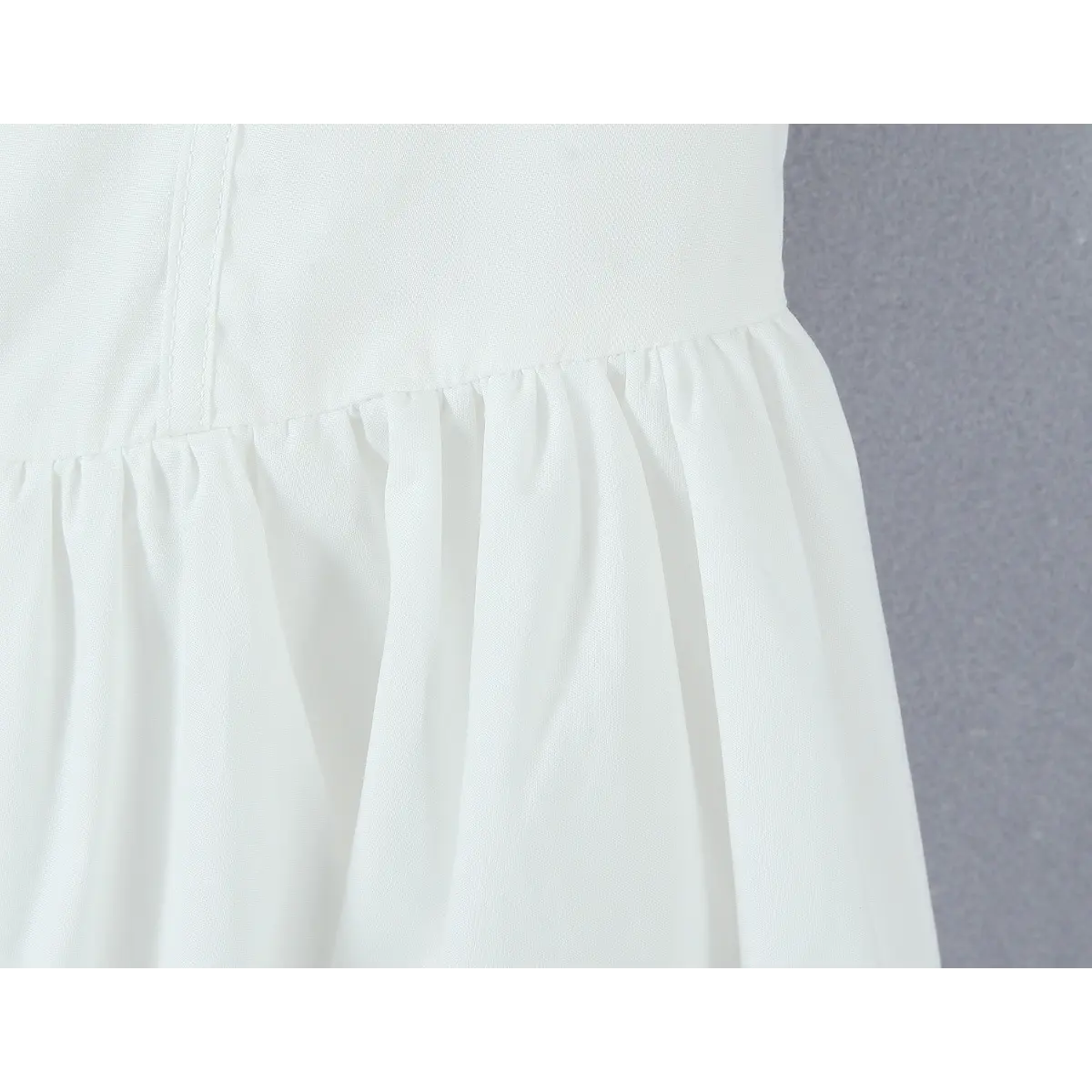 Close-up of the gathered waist seam connecting the bodice to the skirt.