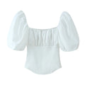 Studio white background full front shot of white square neck crop blouse, elastic gathered bust, balloon puff short sleeves, mixed woven & rib knit fabric, curved shark hem slim fit top