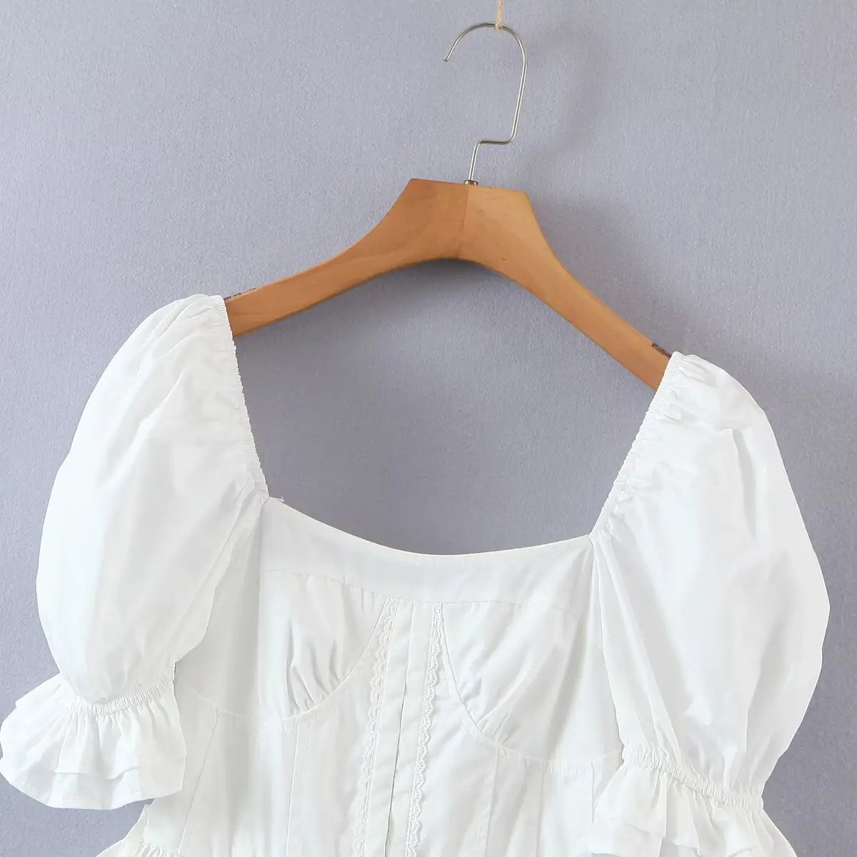 Close-up of the square neckline, lace-trimmed bust cups, and gathered puff sleeves.