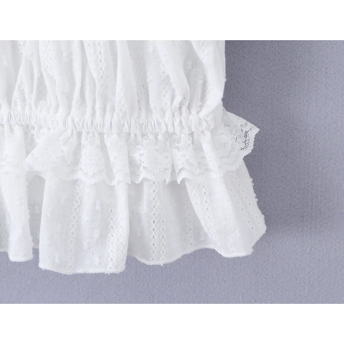 Close-up of the layered peplum hem, featuring intricate floral lace and eyelet embroidery.