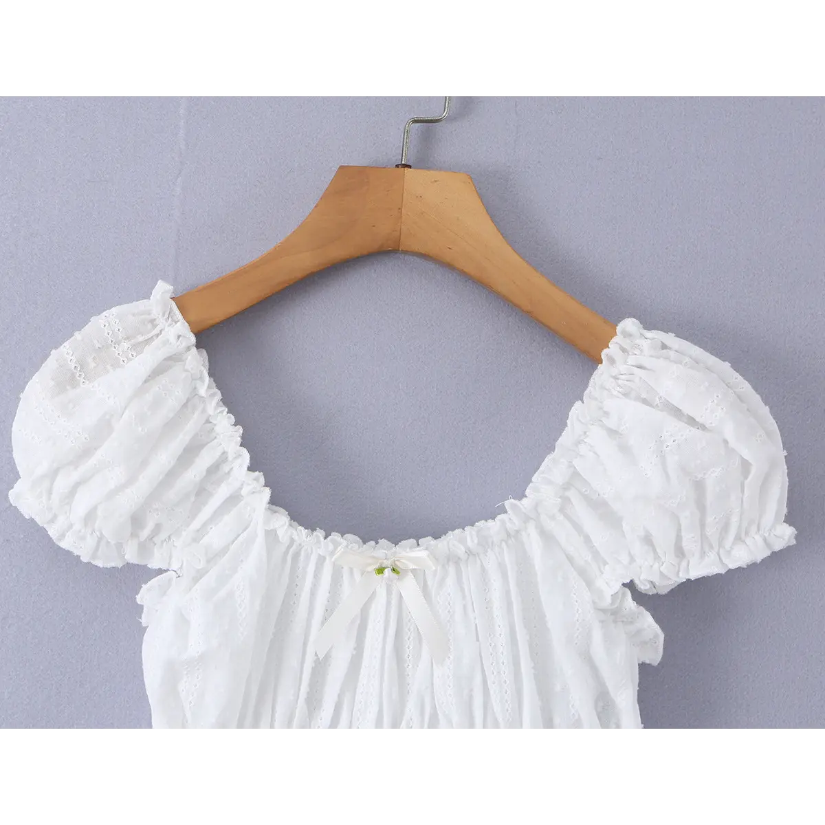 Close-up of the square neckline and front bow, highlighting the gathered fabric and delicate lace trim.