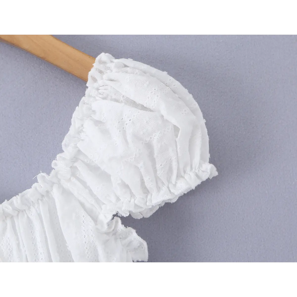 Close-up of the puff sleeve, showcasing the ruched fabric, ruffled trim, and eyelet embroidery.
