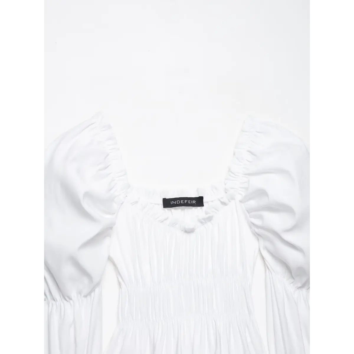 Front shot of the white top, showing the brand label at the neckline and tiered bell sleeves.