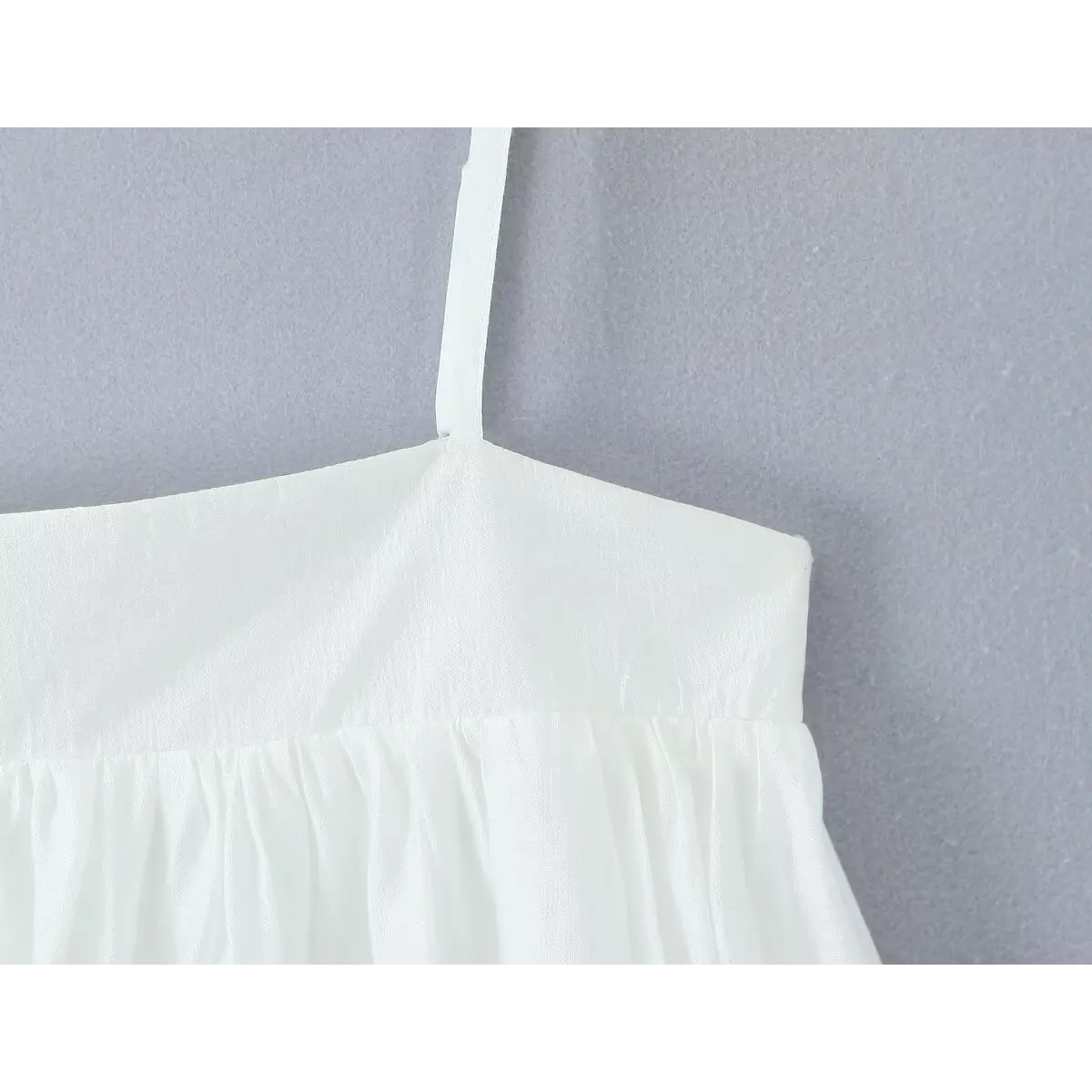Close-up of the side of the square neckline, showing the smocked bodice transition to the gathered skirt.